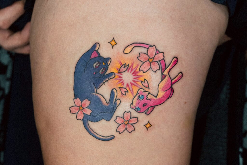 Crossover tattoo of Mew and Jiji with soft colors and sakura details, created at Good Times Ink Osaka.