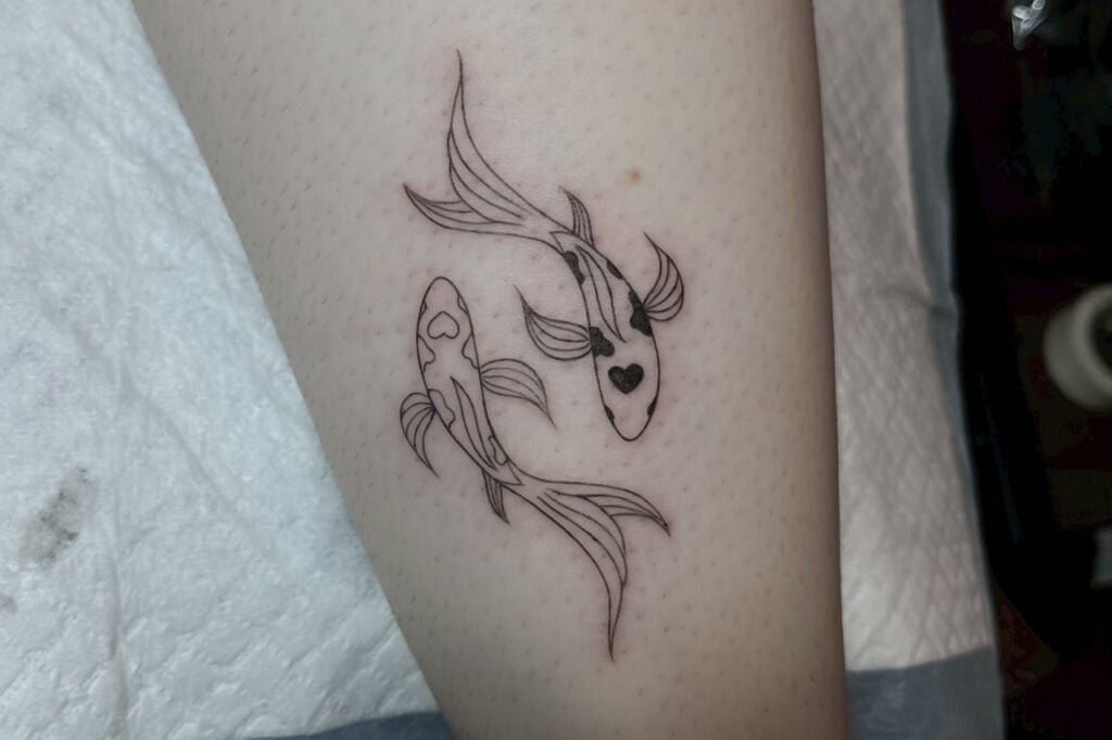 Minimal linework koi tattoo forming a yin–yang shape, created at Good Times Ink Osaka.