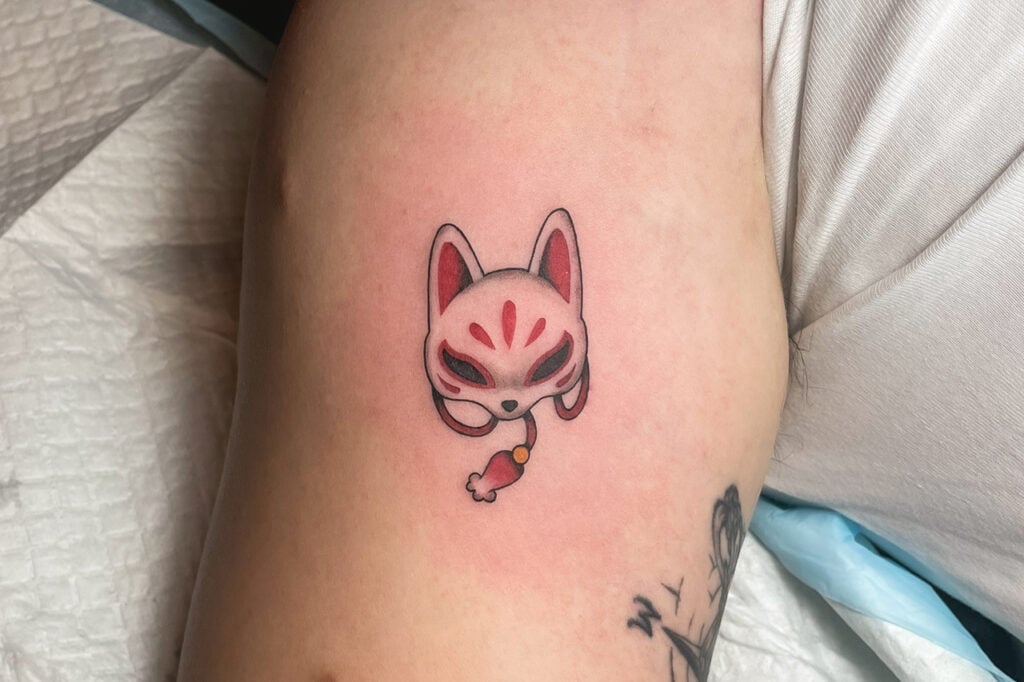 Kitsune mask tattoo with katana and sakura flowers, created at Good Times Ink Osaka.