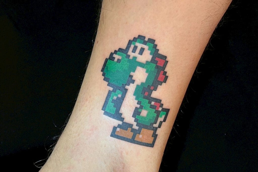 Pixel-art Yoshi tattoo with a retro 8-bit design, created at Good Times Ink Osaka.