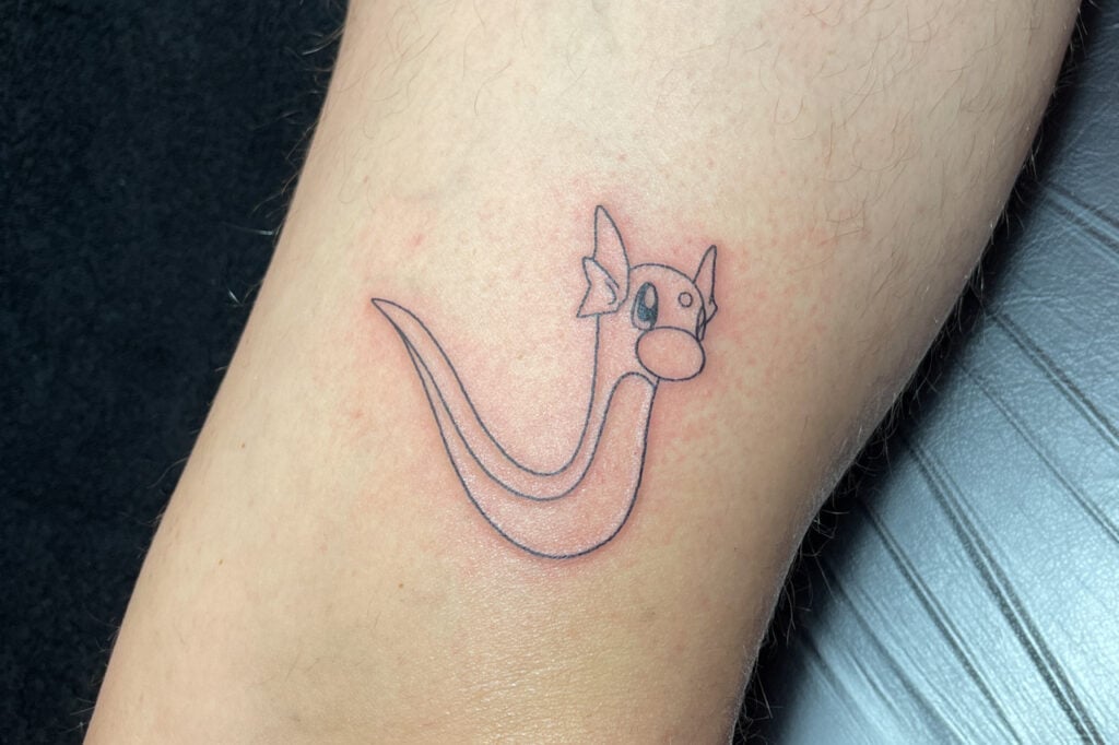 Minimal linework Dratini tattoo with a cute, simple silhouette, created at Good Times Ink Osaka.