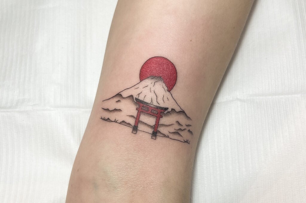 Minimal Mount Fuji tattoo with red sun and torii gate, created at Good Times Ink Osaka.