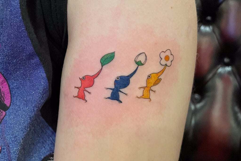 Three-color Pikmin tattoo (red, blue, yellow) in a simple lineup, created at Good Times Ink Osaka.