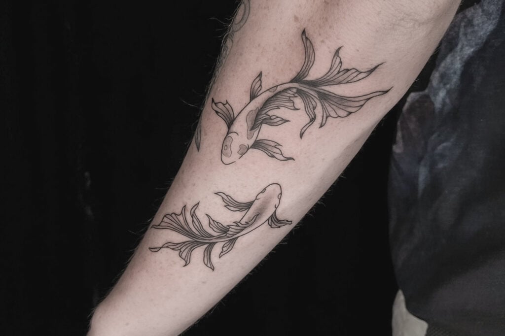 Flowing yin–yang koi tattoo with long fins, created at Good Times Ink Osaka.