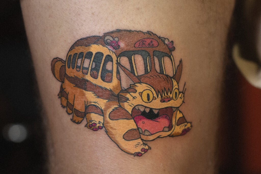 Catbus motif tattoo emphasizing the iconic grin and windows, Osaka.
