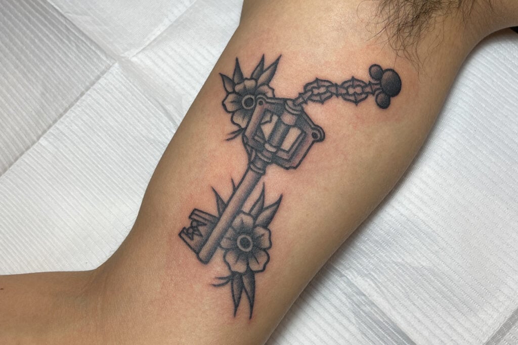 Black and grey American Traditional Keyblade tattoo with bold outlines and floral elements, created at Good Times Ink Osaka.