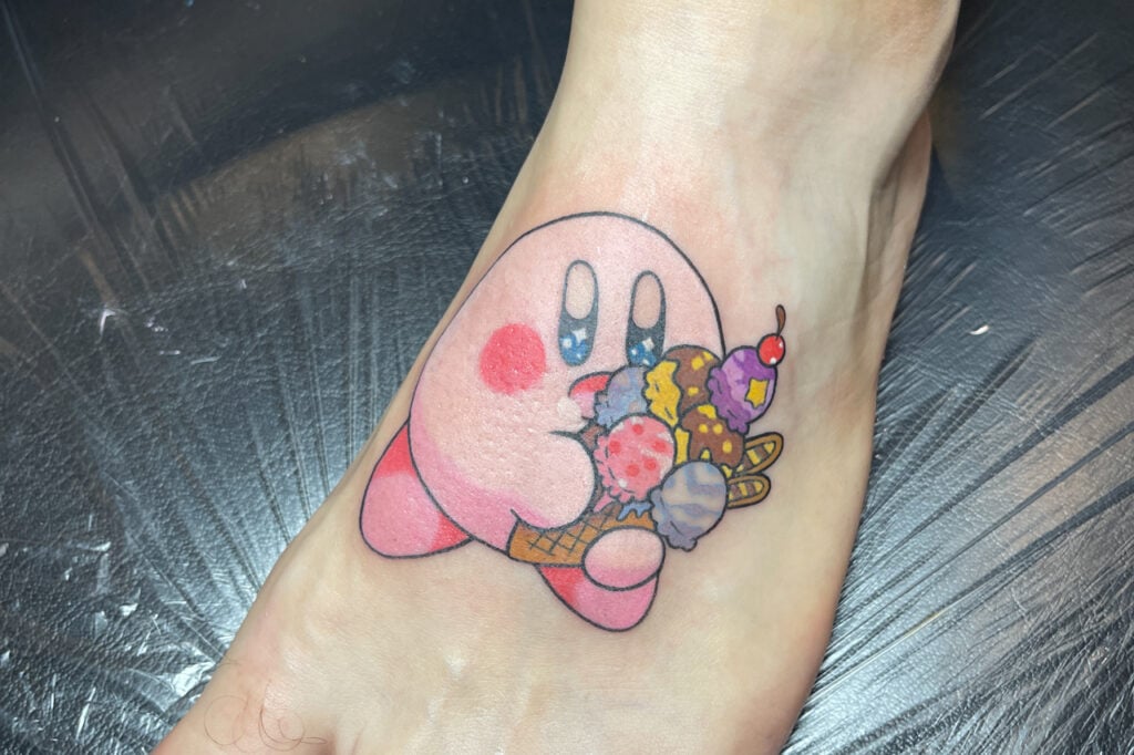 Pastel-colored Kirby tattoo holding ice cream, featuring soft milky tones, created at Good Times Ink Osaka.