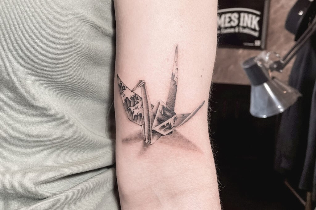 Origami crane tattoo with Hokusai wave pattern inside the wings, created at Good Times Ink Osaka.