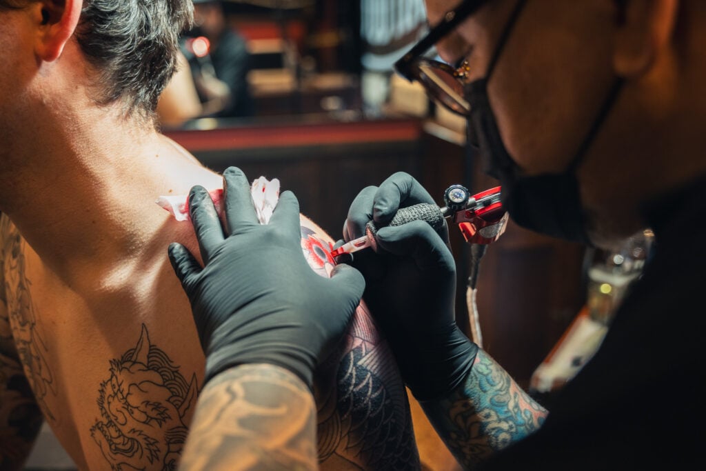 骨に近い、肩のタトゥーの施術風景